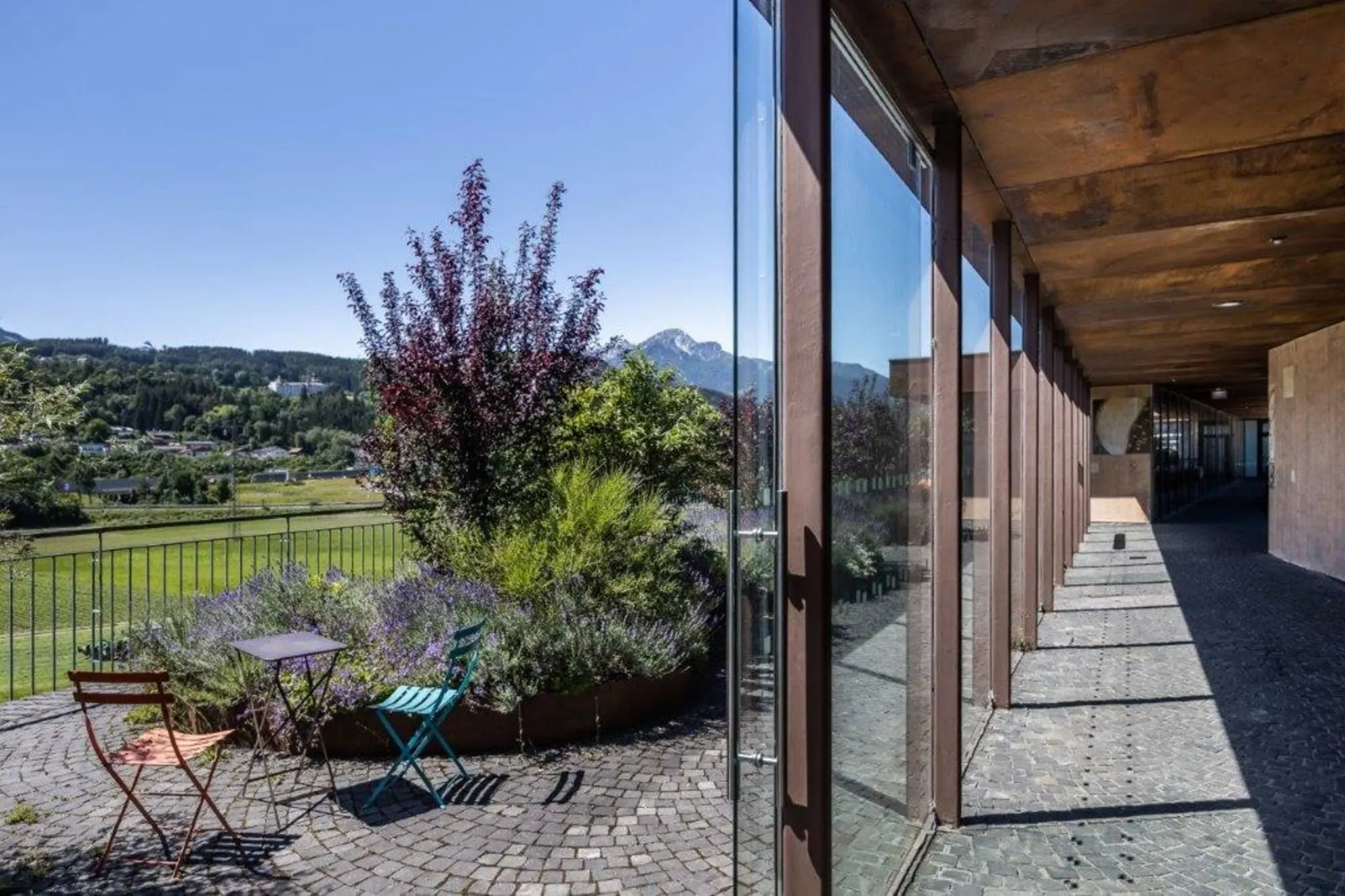 Begrünte Dachterrasse des SOHO 2.0 mit Sitzplätzen, dahinter die Berge